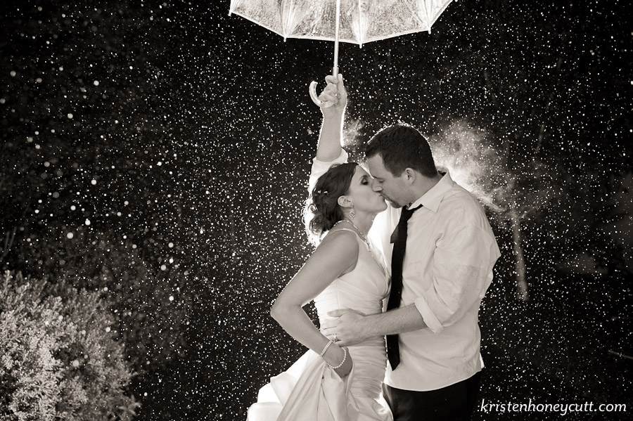 The bride and groom take adantage of a rainy night at their wedding reception.
