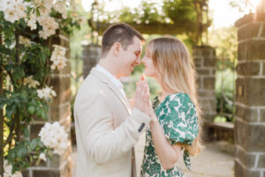 engaged couple smiling closely at each other in a rose garden