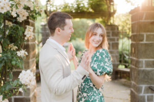 couple laughing and holding hands in a rose garden