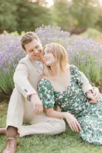 engaged couple sitting in the lavender smiling at each other
