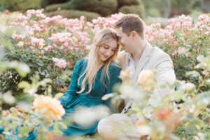 engaged couple sitting and snuggling in a rose garden